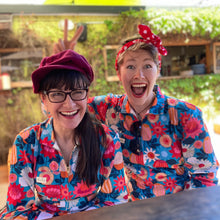 Load image into Gallery viewer, Two happy women wearing colourful floral jumpsuits sitting in a garden cafe.
